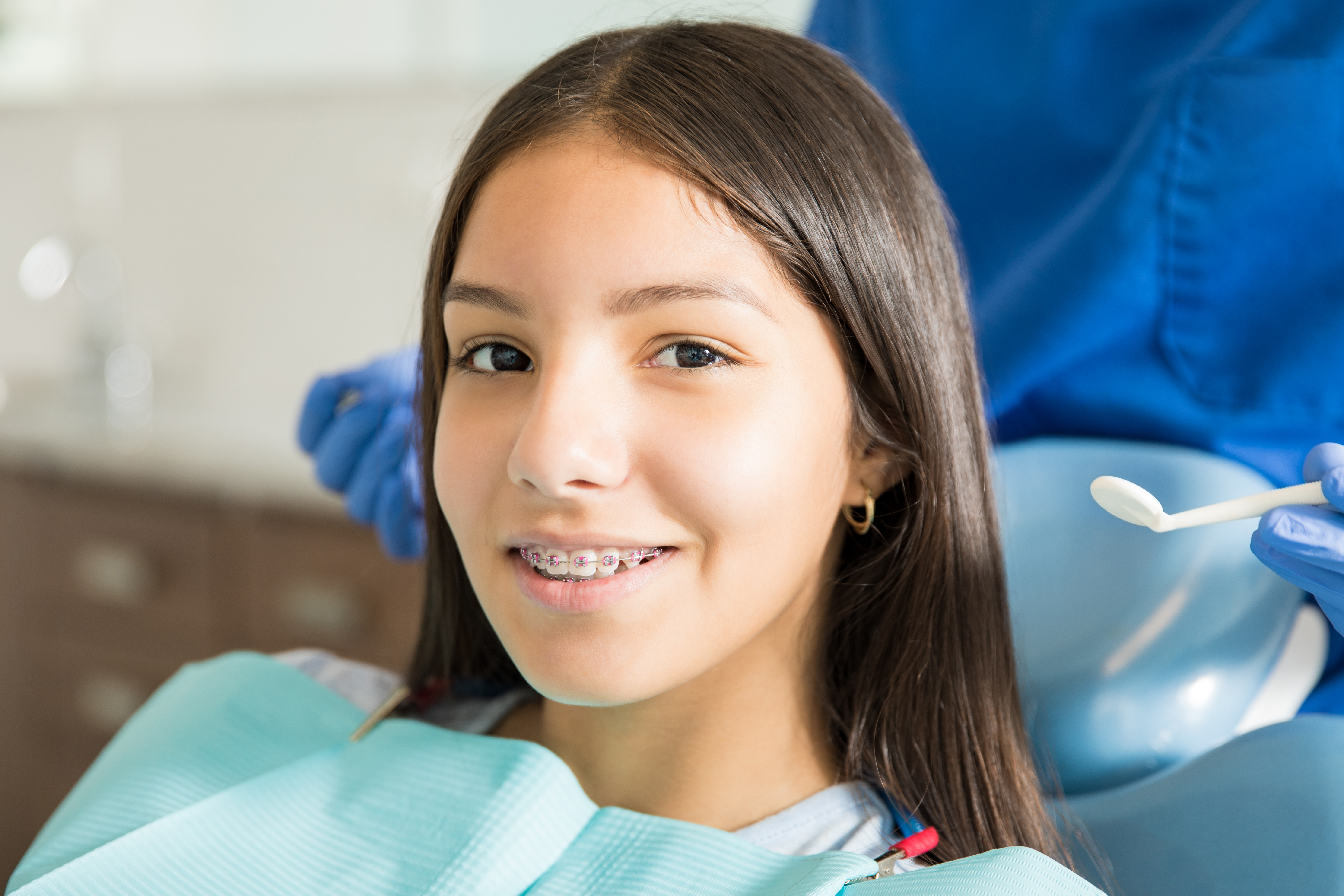 close-up-portrait-smiling-teenage-girl-with-braces-against-dentist-standing-clinic